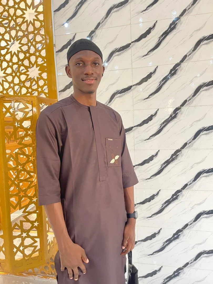 Portrait of Ustadh Ibraheem Ibraheem Babatunde beside a gold Islamic lattice screen