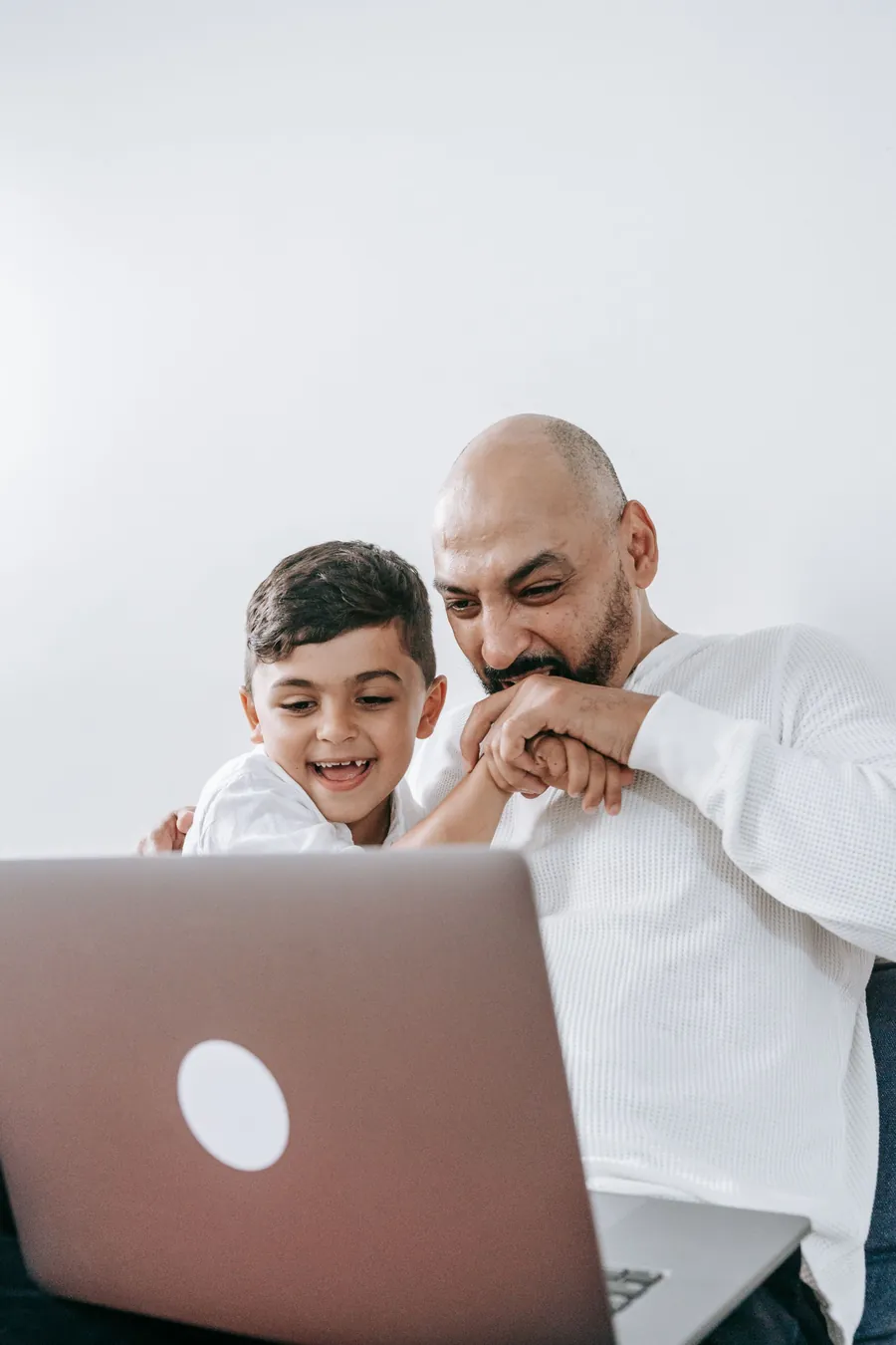 A father and son smiling together during an online lesson